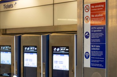 Çağdaş Londra Metro İstasyonu tabelaları ve bilet bariyerlerinin görüntüsü, günlük banliyö ve gezginler için net talimatlar ve bilgiler sunuyor.