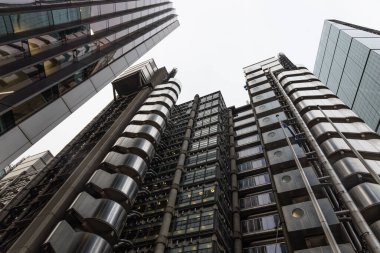 Londra 'daki Lloyds binasına dramatik bir alçak açı, yüksek teknolojili endüstriyel mimari, dış asansörler ve metalik çelik ön cephe.