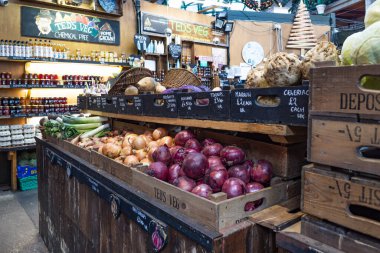 Londra 'daki Borough Market' te bir sebze tezgahı. Kırsal ahşap kasalarda taze kırmızı ve kahverengi soğanlar var. Londra, İngiltere, 17 Aralık 2023