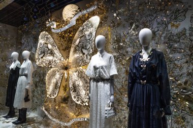 Şen şakrak Christian Dior vitrin vitrininde zarif mankenler ve etrafı şenlikli dekorlarla çevrili devasa bir altın kelebek yapısı sergileniyor. Londra, İngiltere, 17 Aralık 2023