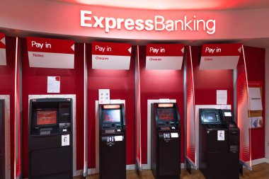 Kırmızı ekspres bankacılık bölgesinde modern otomatik veznedarlar. Banka şubesinde mevduat ve para çekmek için self-servis büfeleri. Londra, İngiltere, 24 Aralık 2023