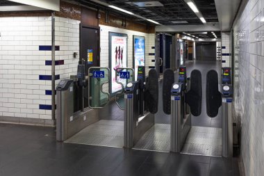 Modern metal turnikeler ve beyaz kiremitli duvarların bulunduğu bir Londra metro istasyonunda boş bilet engelleri. Londra, İngiltere, 25 Aralık 2023