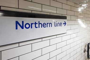 Londra metro istasyonunda beyaz kiremitli bir duvardaki Kuzey Hattı yön işaretinin detaylı görüntüsü.