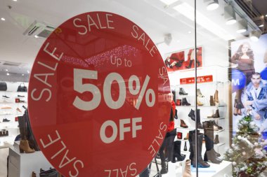 Camcı camındaki kırmızı dairesel satış etiketinin yüzde 50 indirimi var. Arka planda ayakkabı rafları olan bulanık bir perakende. Londra, İngiltere, 31 Aralık 2023