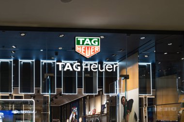 Bir alışveriş merkezinde aydınlatılmış logo ve modern mağaza önü tasarımının yer aldığı bir TAG Heuer lüks saat butiğinin dış görünüşü. Londra, İngiltere, 10 Şubat 2024