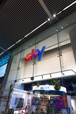 Modern bir alışveriş merkezindeki Sky mağazasının girişinin düşük açılı görüntüsü, cam cephede renkli bir marka logosu var. Londra, İngiltere, 10 Şubat 2024