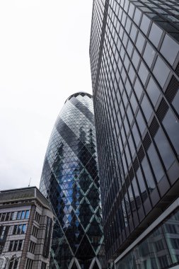 Düşük açılı bakış açısı ikonik Gherkin gökdelenine bakıyor, 30 St. Mary Axe, modern ofis binaları tarafından çerçevelenmiş Londra 'nın finans bölgesinde.