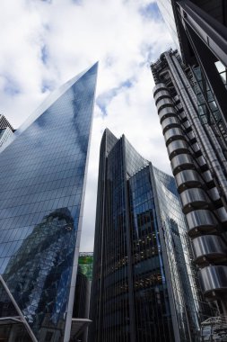 Düşük açılı modern gökdelenler Londra 'nın finans bölgesindeki The Scalpel ve Lloyds binaları bulutlu mavi gökyüzüne karşı.