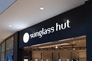 Siyah arka planda beyaz logonun yer aldığı bir güneş gözlüğü mağazasının dış görünüşü. Alışveriş merkezi ortamında modern gözlük mağazası girişi. Londra, İngiltere, 17 Şubat 2024