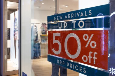 Mağaza vitrininin önünde yüzde 50 indirimli büyük kırmızı bir tabela var. Moda mağazasında indirimli satış promosyonu. Yeni gelenlerin metinleri camdan görülebiliyor. Londra, İngiltere, 17 Şubat 2024