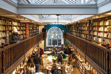 İnsanlar Londra 'daki ünlü Daunt Kitapçısının içine bakıyorlar. Ahşap balkonları, sıcak ışıklandırması ve geniş bir edebiyat koleksiyonu olan klasik bağımsız bir kitapçı. Londra, İngiltere, 25 Şubat 2024