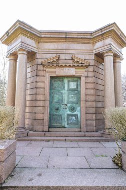 Londra 'daki Highgate Mezarlığı' nda yeşil bronz kapılı klasik taş bir mozolenin önü. Tarihi Viktorya dönemi mezarlığı mimarisi. Londra, İngiltere, 3 Mart 2024