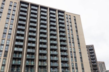 Modern apartman dış hatları, tekrarlanan pencereler ve dikey tasarım, çağdaş kentsel yerleşim mimarisini temsil ediyor..