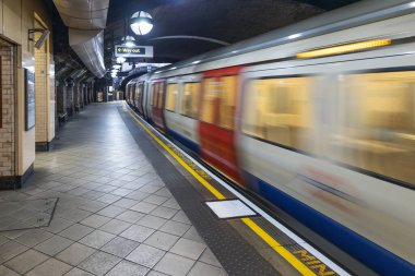 Yüksek hızlı bir tren, Londra metro platformundan geçerken hareket bulanıklığı yaratır. Londra, İngiltere, 1 Nisan 2024