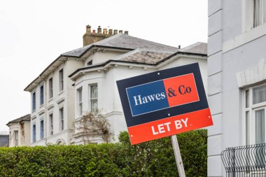 Bir banliyö caddesinde beyaz konutların önünde kırmızı ve mavi bir levha duruyor. Londra, İngiltere, 6 Nisan 2024