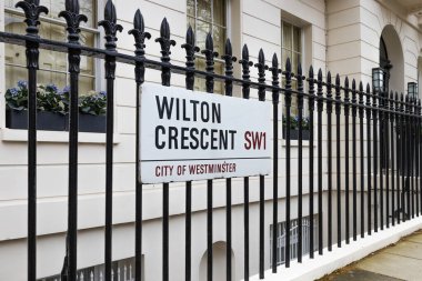 Wilton Crescent 'in sokak tabelası Westminster, Londra, SW1 bölgesindeki siyah dövmeli demir bir çite asılmış..