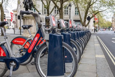 Santander Bisikletleri Londra caddesindeki bir rıhtım istasyonuna park etmiş. Şehir içi taşıma ve şehir seyahati için bisiklet paylaşım şeması. Londra, İngiltere, 14 Nisan 2024
