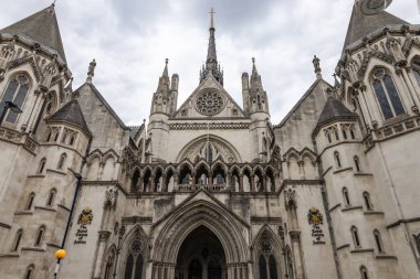 Londra 'da bulutlu bir gökyüzünün altında Adalet Sarayı' nın süslenmiş Viktorya dönemi Gotik taş cephesine geniş bir bakış açısı. Londra, İngiltere, 5 Mayıs 2024