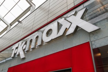 Kentsel bir alışveriş bölgesindeki modern bir perakende mağazasının girişindeki kırmızı duvara büyük beyaz bir Tk Maxx tabelası asıldı. Londra, İngiltere, 5 Mayıs 2024