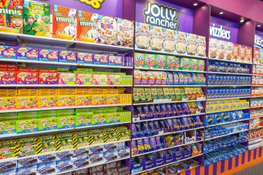 Mor perakende raflarda düzenlenmiş çeşitli parlak paketlenmiş Amerikan şekerleri, çikolatalar ve kahvaltı gevrekleri. Londra, İngiltere, 2 Haziran 2024