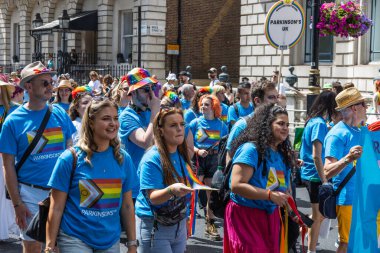 A group of people wearing blue shirts with rainbow graphics walk through the streets of London during the 2024 Pride parade celebration. London, UK, 29 June 2024