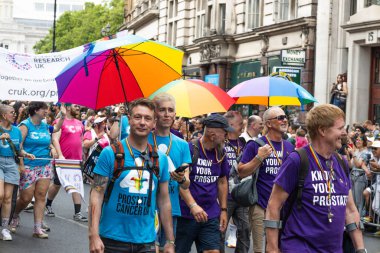 Geleneksel Onur Yürüyüşü kutlamaları sırasında bir grup insan ellerinde gökkuşağı şemsiyeleriyle Londra sokaklarında yürüyor. Londra, İngiltere, 29 Haziran 2024