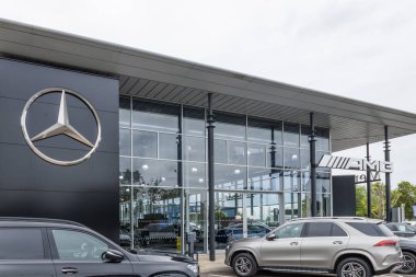 Modern bir Mercedes-Benz araba galerisinde büyük bir cam cephe ve siyah dış duvarda üç köşeli sembolik yıldız logosu bulunur. Portsmouth, İngiltere, 3 Temmuz 2024
