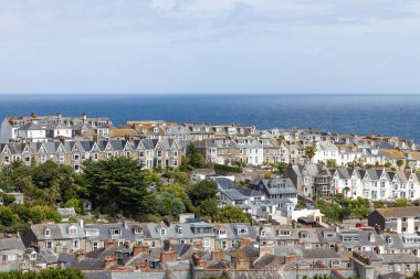 Sahil kasabası St Ives, Cornwall 'daki geleneksel ev ve çatıların geniş hava manzaralı arka planda okyanus ufkuyla mavi gökyüzünün altında..