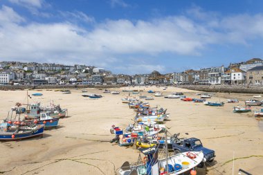 St. Ives limanının alçak gelgit sırasında geniş bir manzarası var. Arkasında renkli tekneler ve arka planda yerel binalar var. St Ives, İngiltere, 4 Temmuz 2024