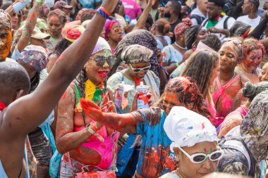 Karayip karnavalının hareketli müziği ve enerjik atmosferinin tadını çıkaran dağınık boyalarla kaplı kalabalık bir mutlu şenlik. Londra, İngiltere, 25 Ağustos 2024