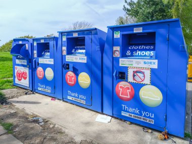 Açık bir alanda hayır amaçlı geri dönüşüm için kullanılmış giysiler ve ayakkabılar toplamak için kullanılan parlak mavi metal bağış kutuları. Londra, İngiltere, 13 Nisan 2024