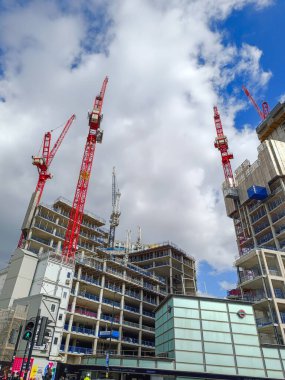 Şehirde devam eden yüksek binalı bir inşaat projesinin görüntüsünde, parlak mavi gökyüzü altında modern mimari üzerinde çalışan büyük inşaat vinçleri sergileniyor. Londra, İngiltere, 15 Nisan 2024