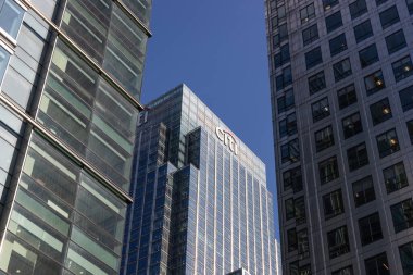 Şehir Kulesi 'nin alçak açılı manzarası ve Canary Wharf, Londra' daki modern şehir silueti olan cam ofis binaları. Londra, İngiltere, 14 Mayıs 2023