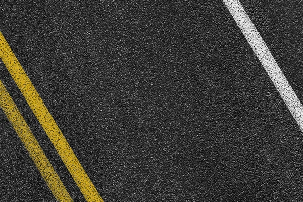 Level asphalted road with a dividing white and yellow stripes. The texture of the tarmac, top view. — Stock Photo, Image