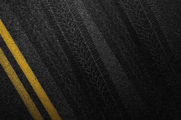 Carretera asfaltada de nivel con franjas amarillas divididas y pistas de neumáticos. La textura de la pista, vista superior . — Foto de Stock