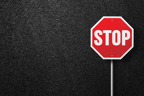 Red road sign with the words STOP on a background of asphalt. The texture of the tarmac, top view. — Stock Photo, Image