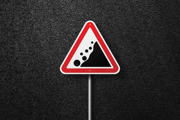 Road sign triangular shape with a picture of the rockfall on a background of asphalt. The texture of the tarmac, top view. — Stock Photo, Image