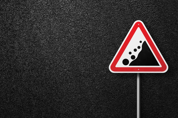 Road sign triangular shape with a picture of the rockfall on a background of asphalt. The texture of the tarmac, top view. — Stock Photo, Image