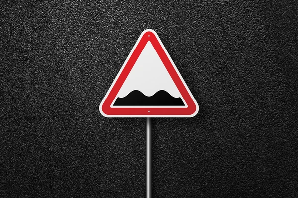 Road sign of the triangular shape on a background of asphalt. Rough roads. The texture of the tarmac, top view. — Stock Photo, Image