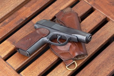 The Makarov pistol and holster lie on wooden boards. clipart