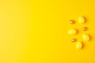 Sarı arka planda Paskalya sarısı yumurtalar. Düz yat, boşluğu kopyala.