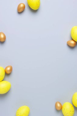 Gri arkaplanda Paskalya sarısı ve altın yumurta. Düz yat, boşluğu kopyala.