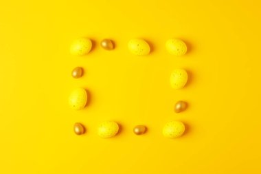 Sarı arka planda Paskalya sarısı yumurtalar. Düz yat, boşluğu kopyala.