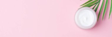 Pembe arka planda yaprak palmiye dalı olan kozmetik kremi kavanozu. Düz yat, boşluğu kopyala