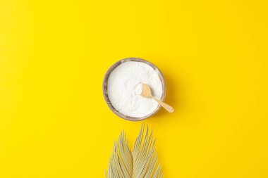 Kasede kolajen tozu ve sarı arka planda palmiye yaprakları olan bir kaşık. Düz yat, boşluğu kopyala
