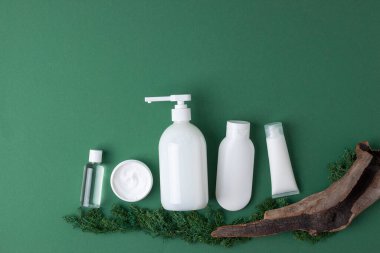 Cilt bakım ürünleriyle kozmetik bileşimi, zeytin yeşili arka planda yosun ve ahşap. Düz yat, boşluğu kopyala