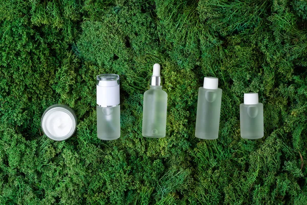 Cosmetic skin care products on green moss natural background. Flat lay, copy space
