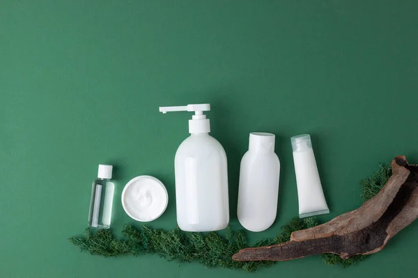 Cosmetic composition with skin care products, moss and wood on olive green natural background. Flat lay, copy space