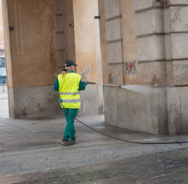 Milan İtalya 27 Şubat 2026: Bir belediye hizmetleri çalışanı yüksek basınçlı su jetiyle yol yüzeyini temizliyor, yüksek görünürlüklü güvenlik giysileri giyiyor