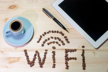 WiFi sembolü kahve çekirdekleri ile yaptı. Ahşap masa üstünde laptop